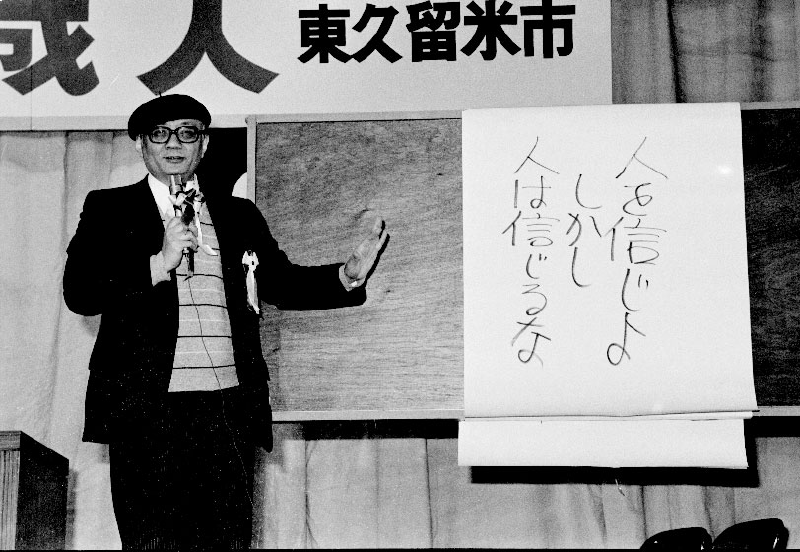 Osamu Tezuka presenting a sign that says "Believe in people, but don't believe people."